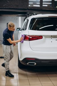 worker car detailing cleaning car with microfiber